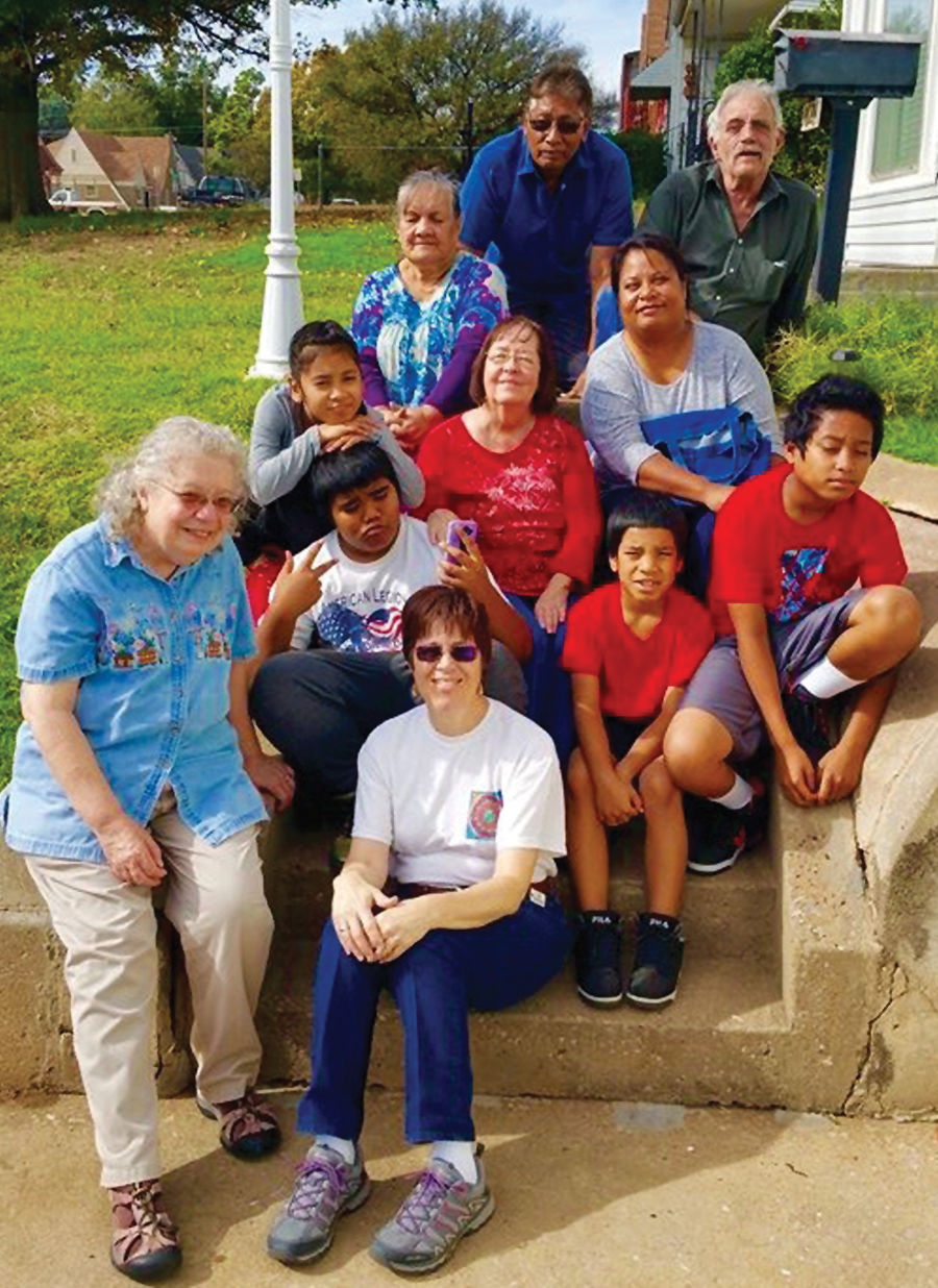 Eleven people assemble on outdoor stairs on a sunny day.