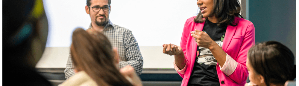 A woman speaks to a class of young adults.