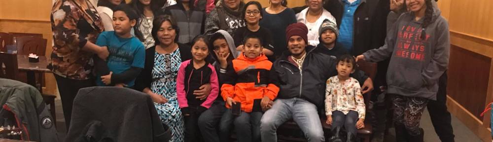 Twenty-five people pose for a group portrait in a community center.