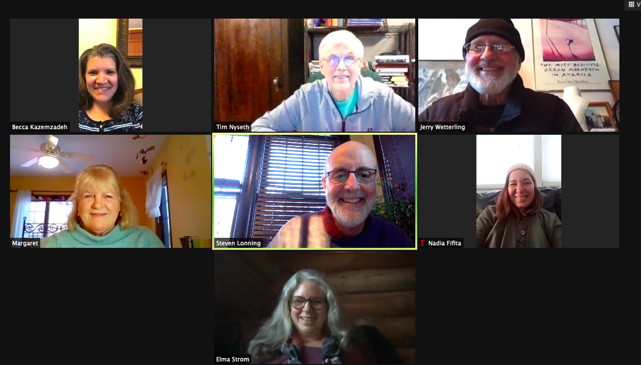 Seven people smile into their webcams on a video call.