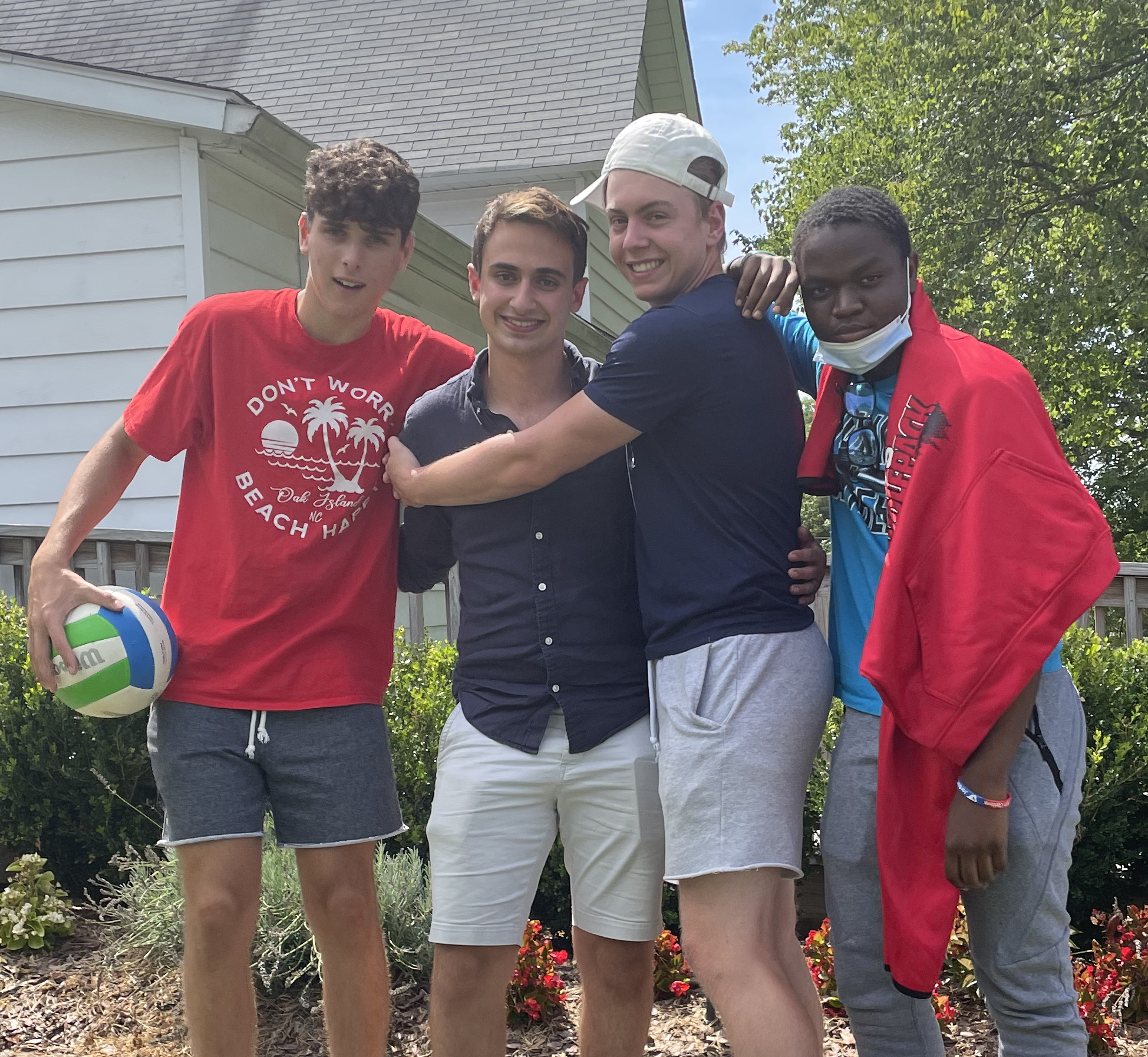 Four young men pose together and smile.