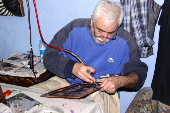 Artisan drilling through layers of colored metal to make an etched platter,