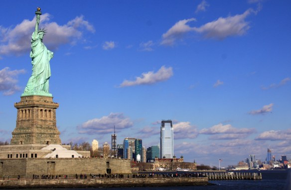 The Statue of Liberty with Ellis Island behind it, taken from a ferry.