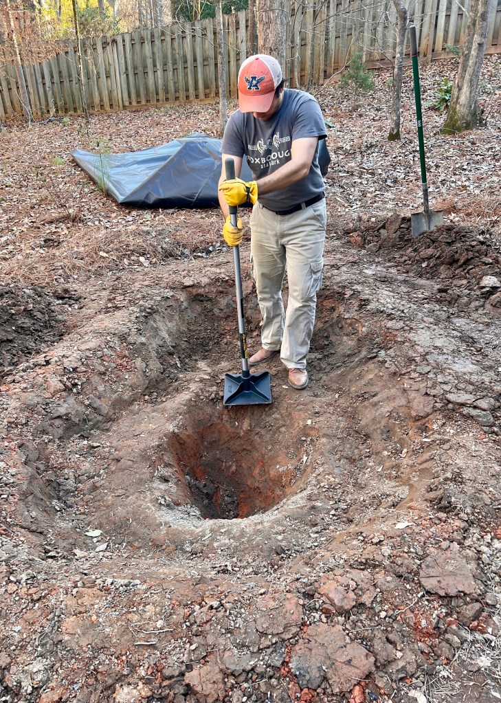 A man uses a tamping tool to compress dirt.