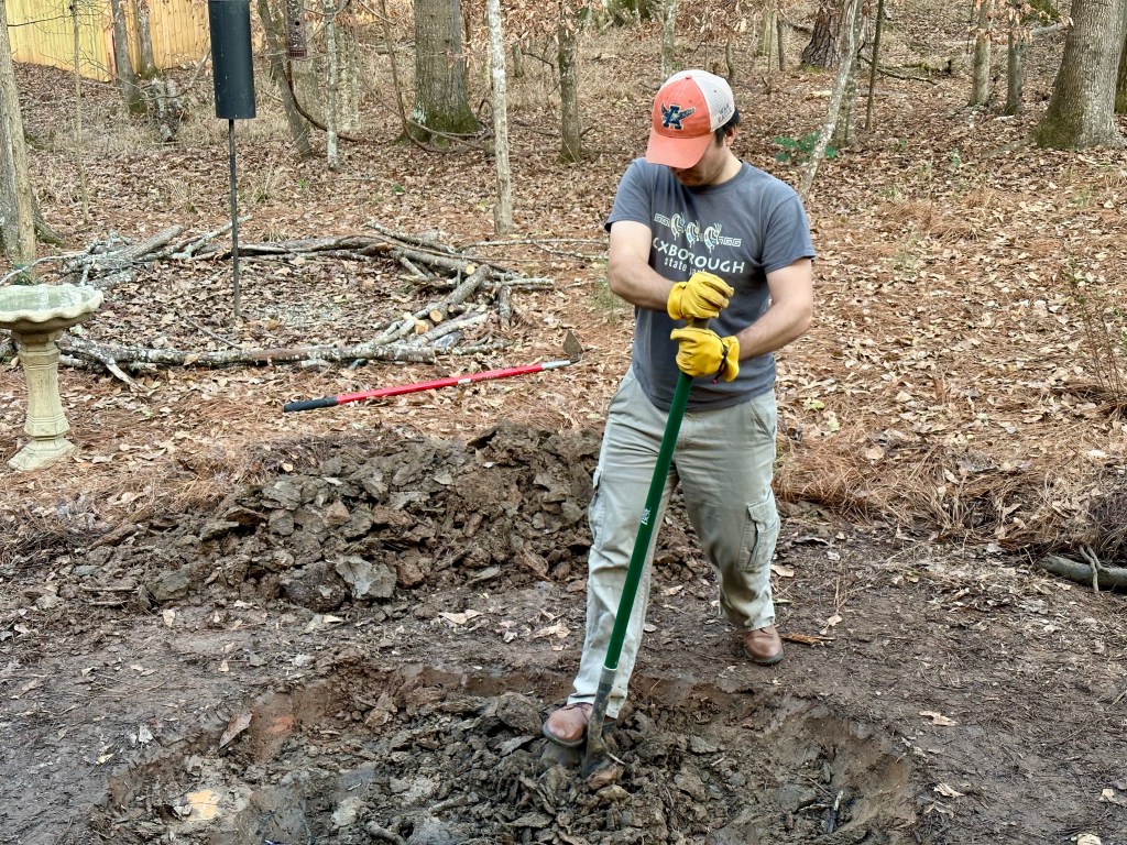 A man digs into soil with a shovel.