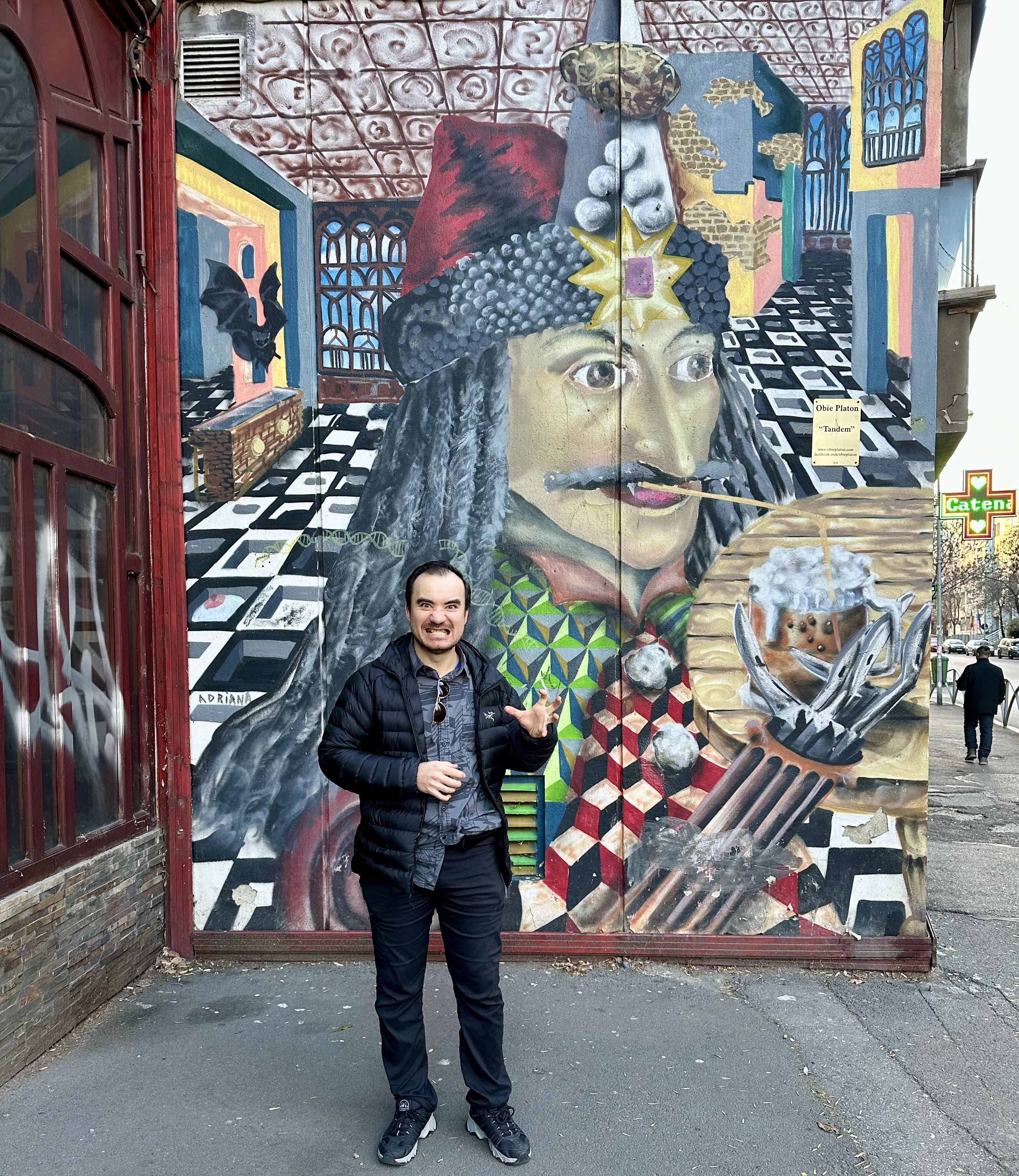 Sergey Miron poses in front of a comical mural depicting a Romanian prince drinking coffee.