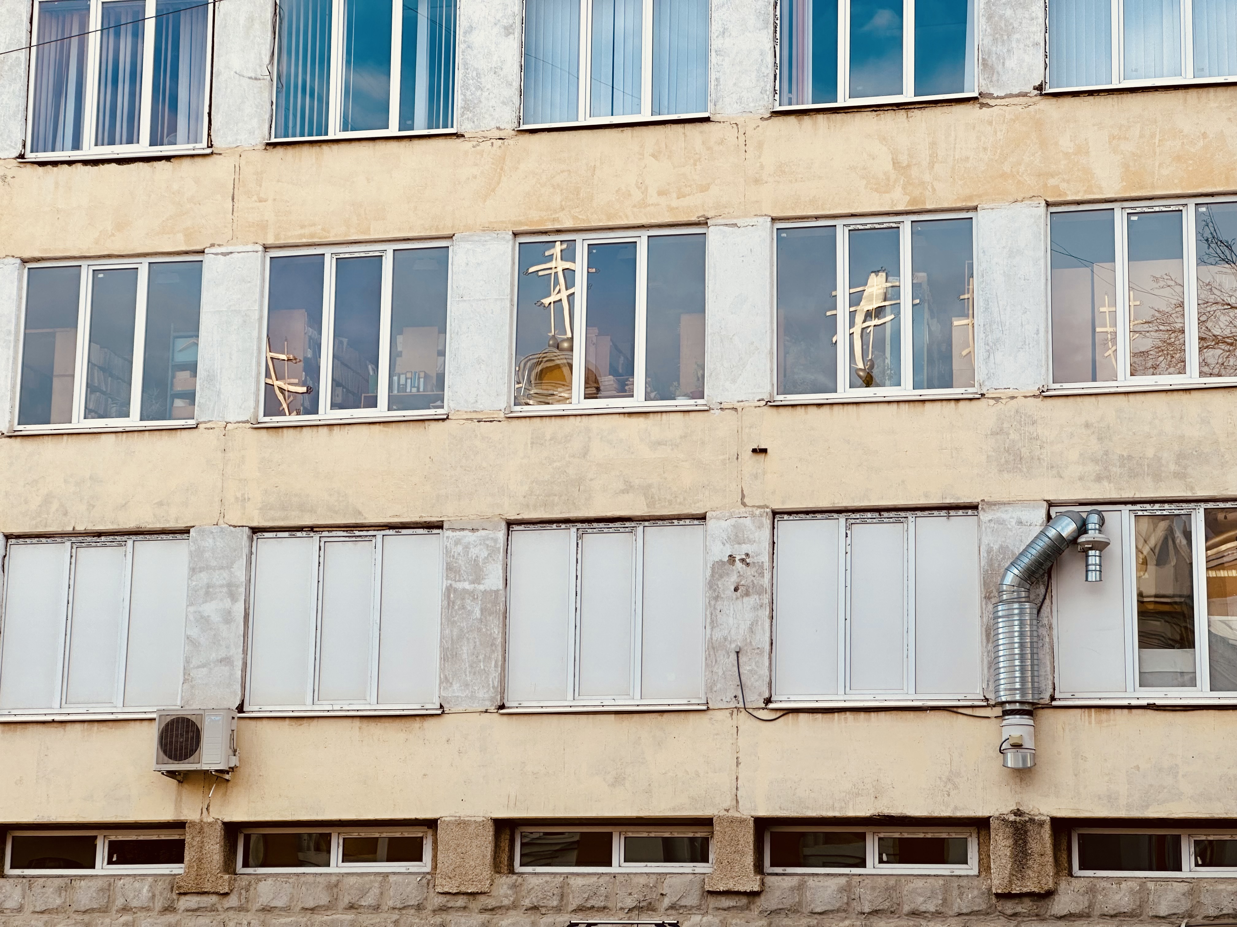 In an academic building's windows, the crosses and golden domes of an Orthodox Christian church reflect.