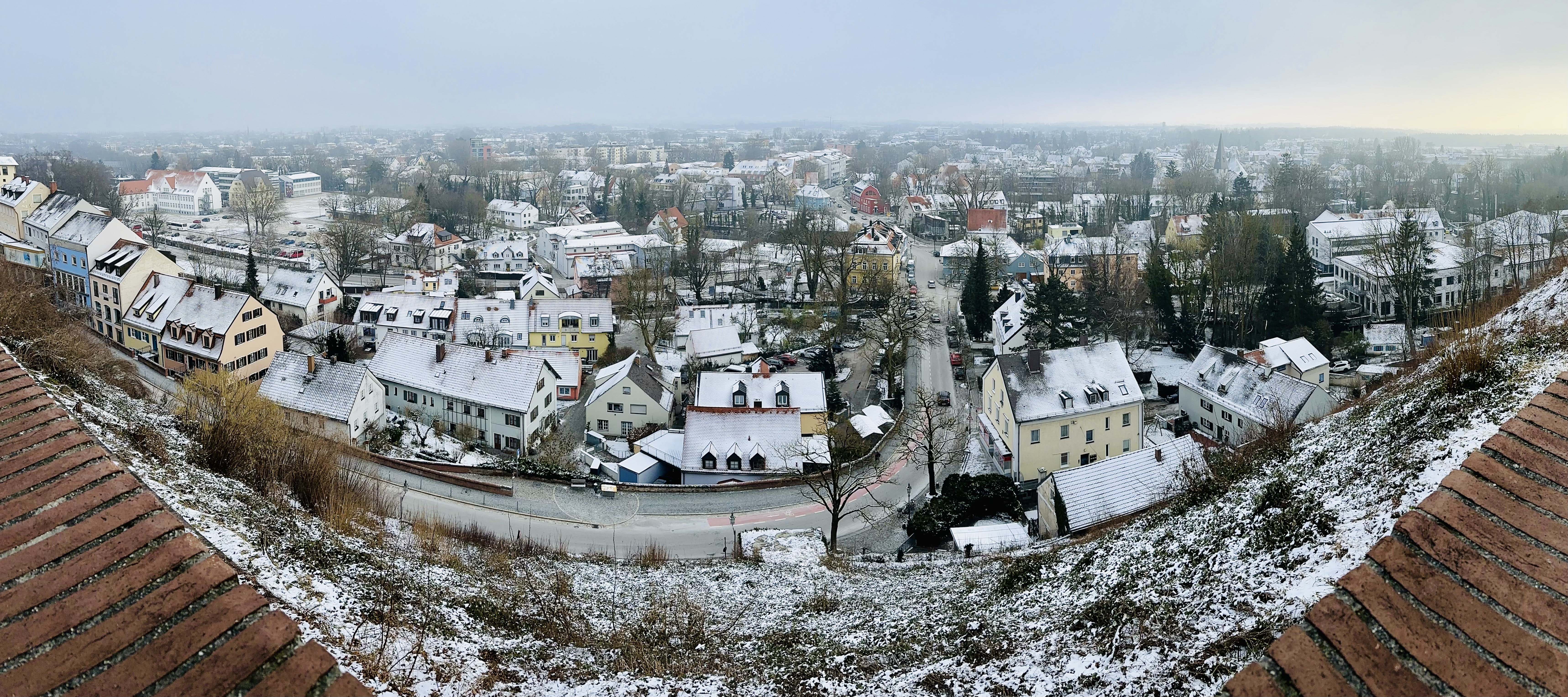 A panorama of colorful stucco buildings with steep roofs dusted with snow.