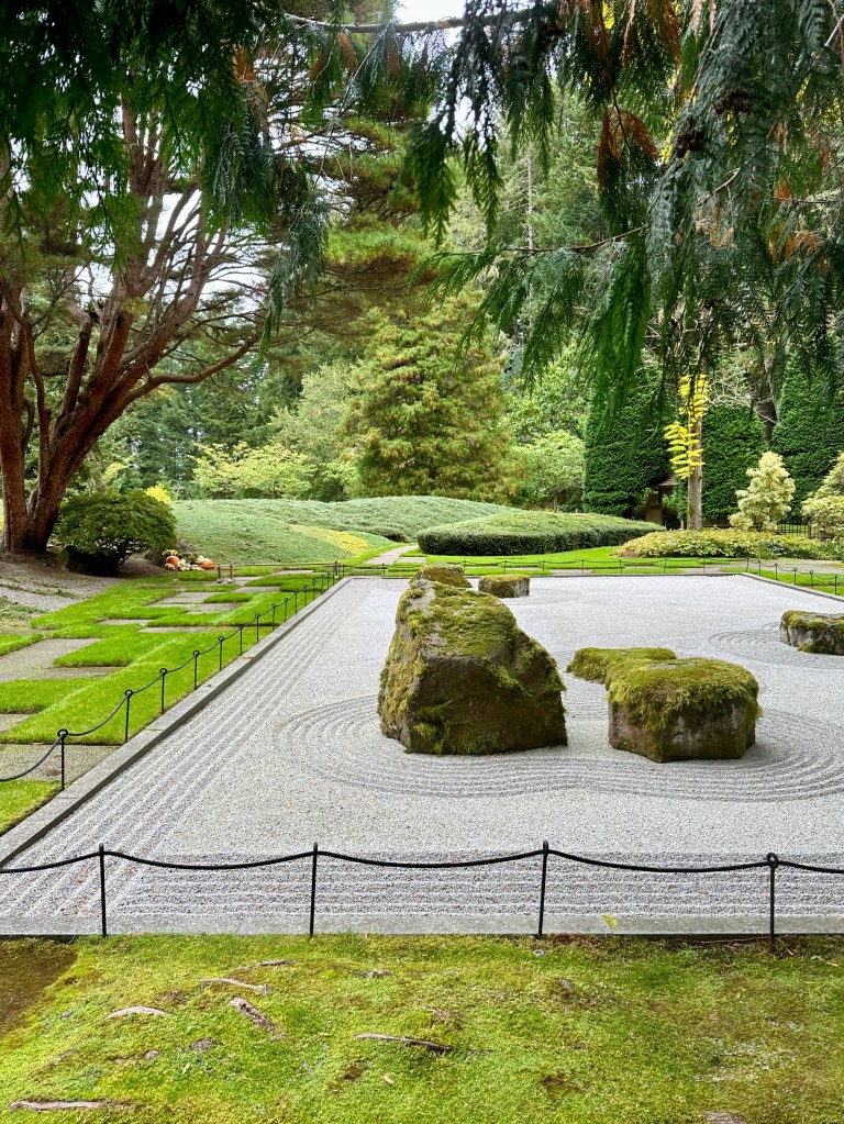 A Zen garden has mossy boulders and carefully raked pebbles.