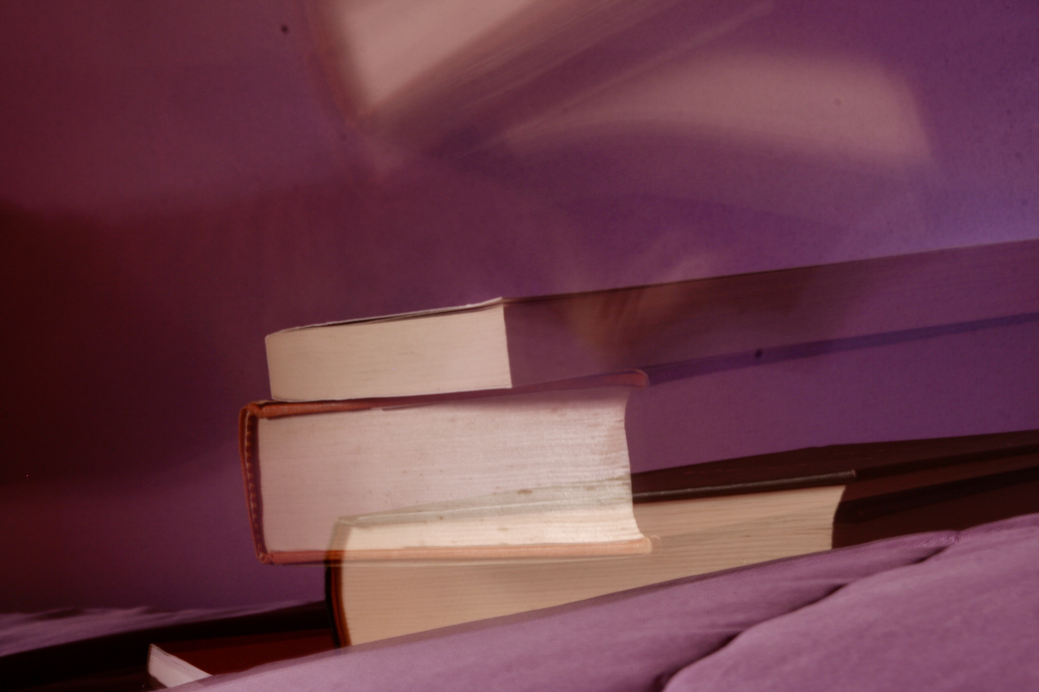 In front of a stack of several books, a ghostly arm holds a book aloft.