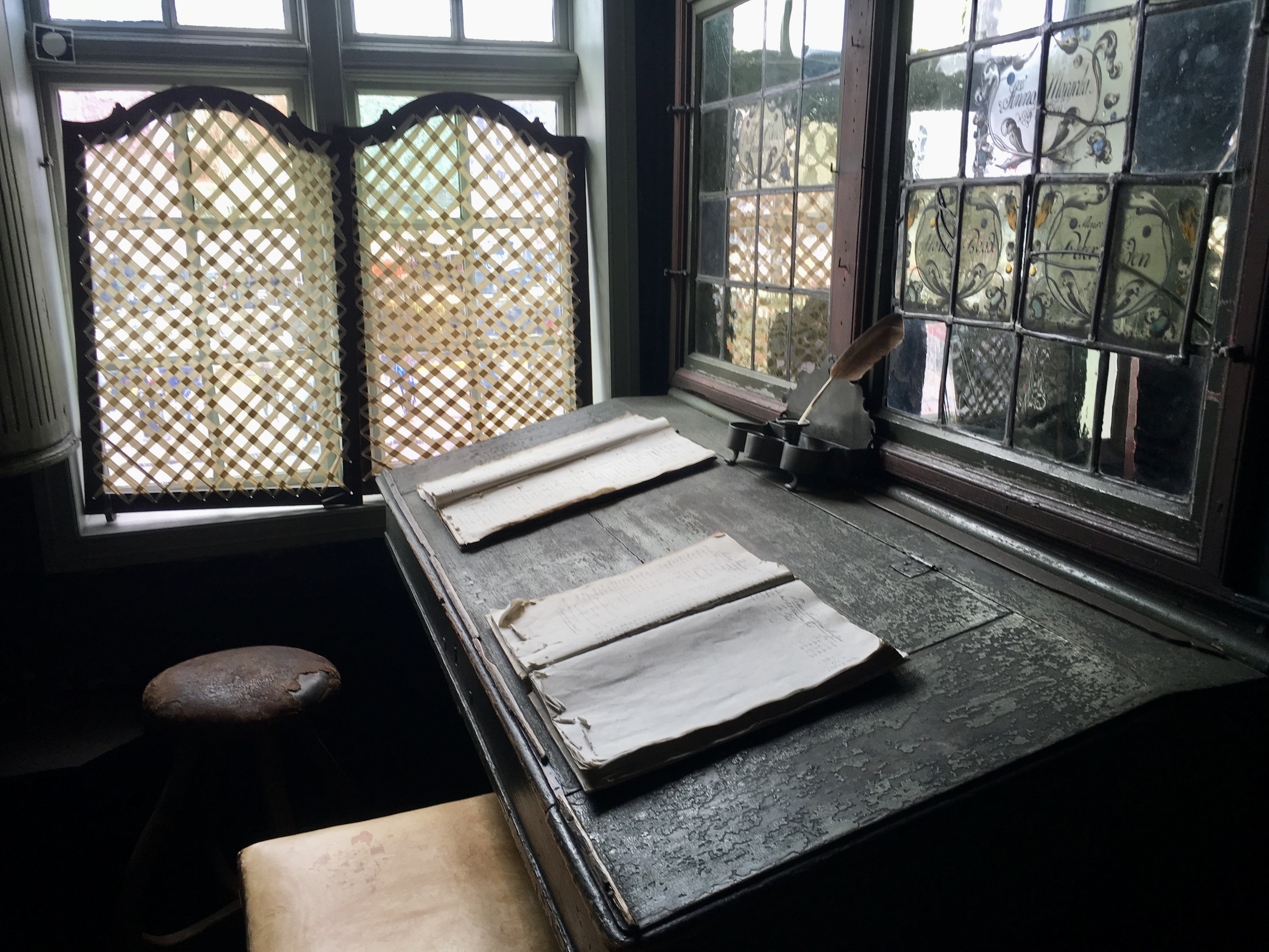 Two tattered ledgers sit open on an antique desk.