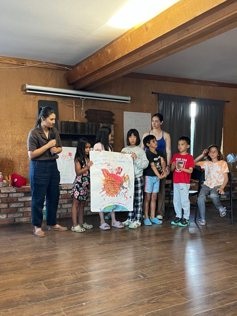 A group of children and teachers presenting their artwork to an audience.