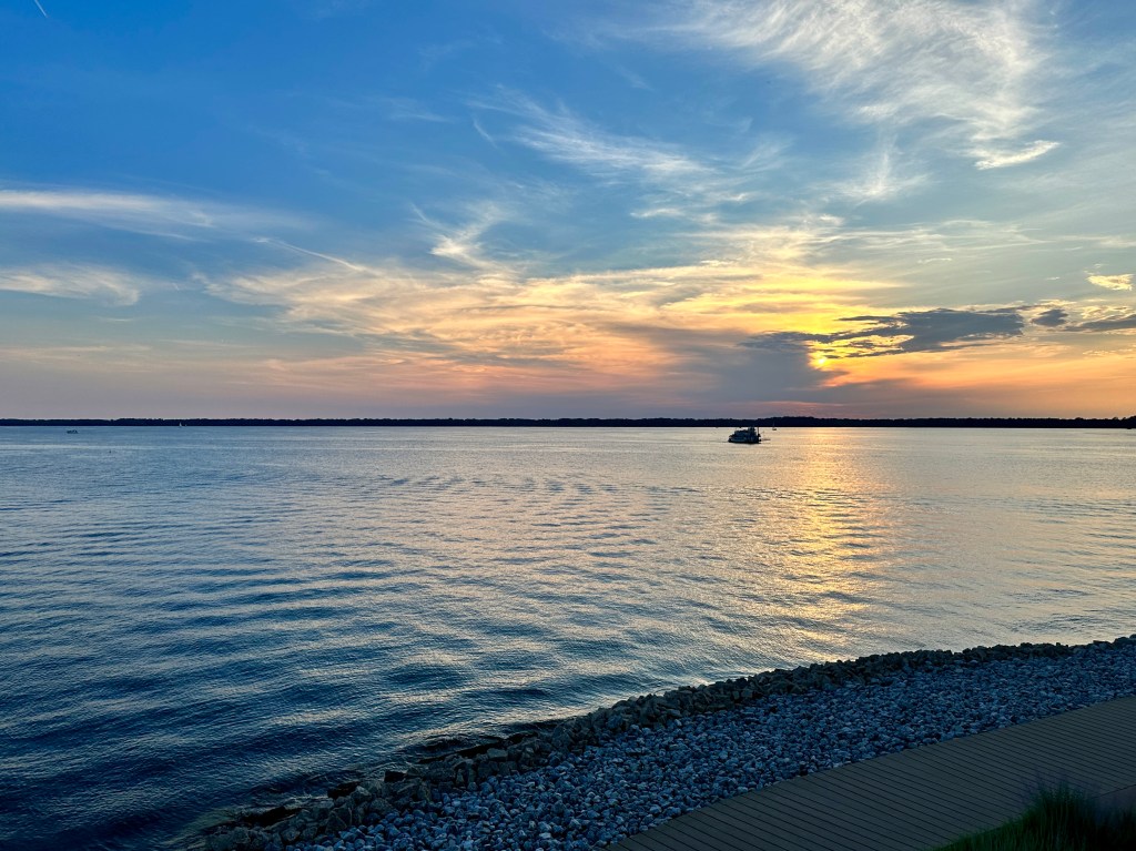 A boat crosses a bay at sunset.