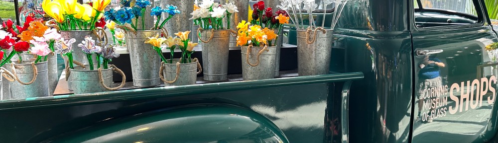An old-fashioned pickup truck holds buckets of glass flowers.