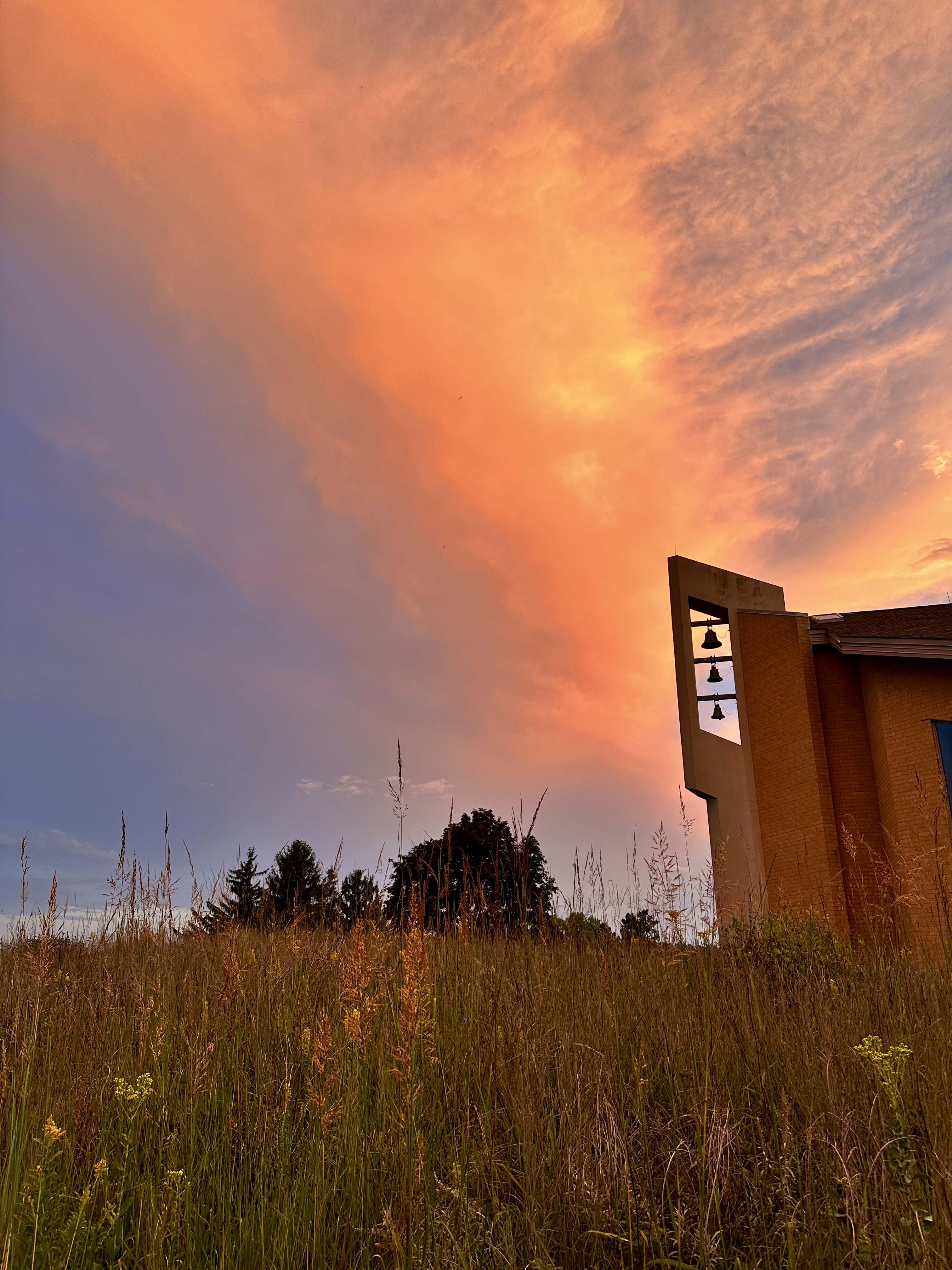 Clouds lit by sunset appear behind a monastery's bell tower.
